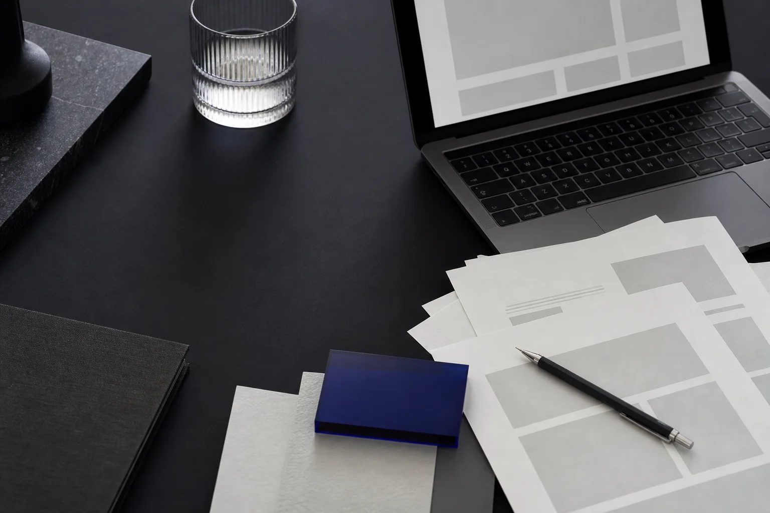Mörk designstudio med skisser, laptop och materialprover för webbdesign